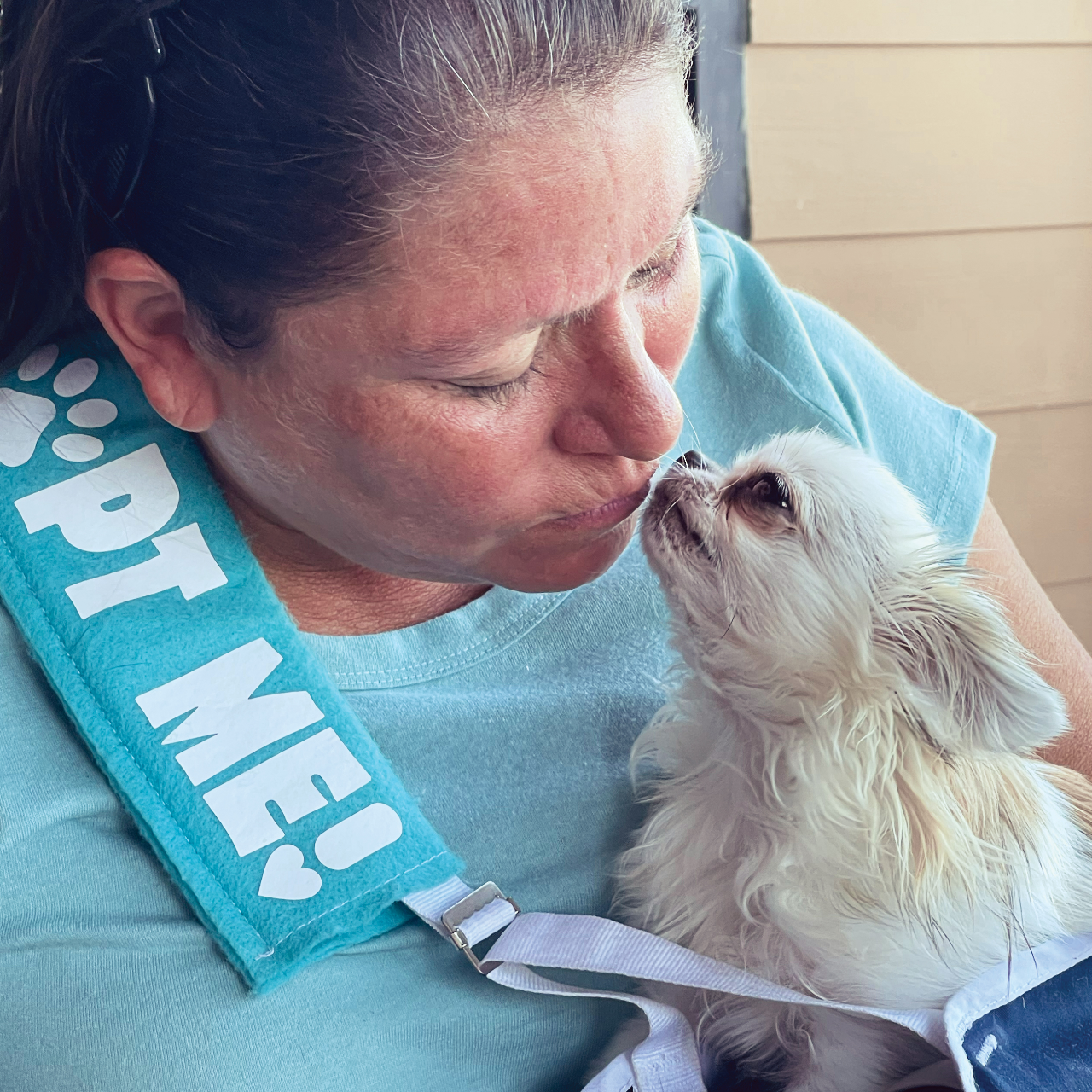 woman making a kissy face at an adoptable chihuahua sitting in her lap